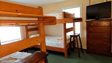Una habitación con literas y un televisor sobre un aparador.
