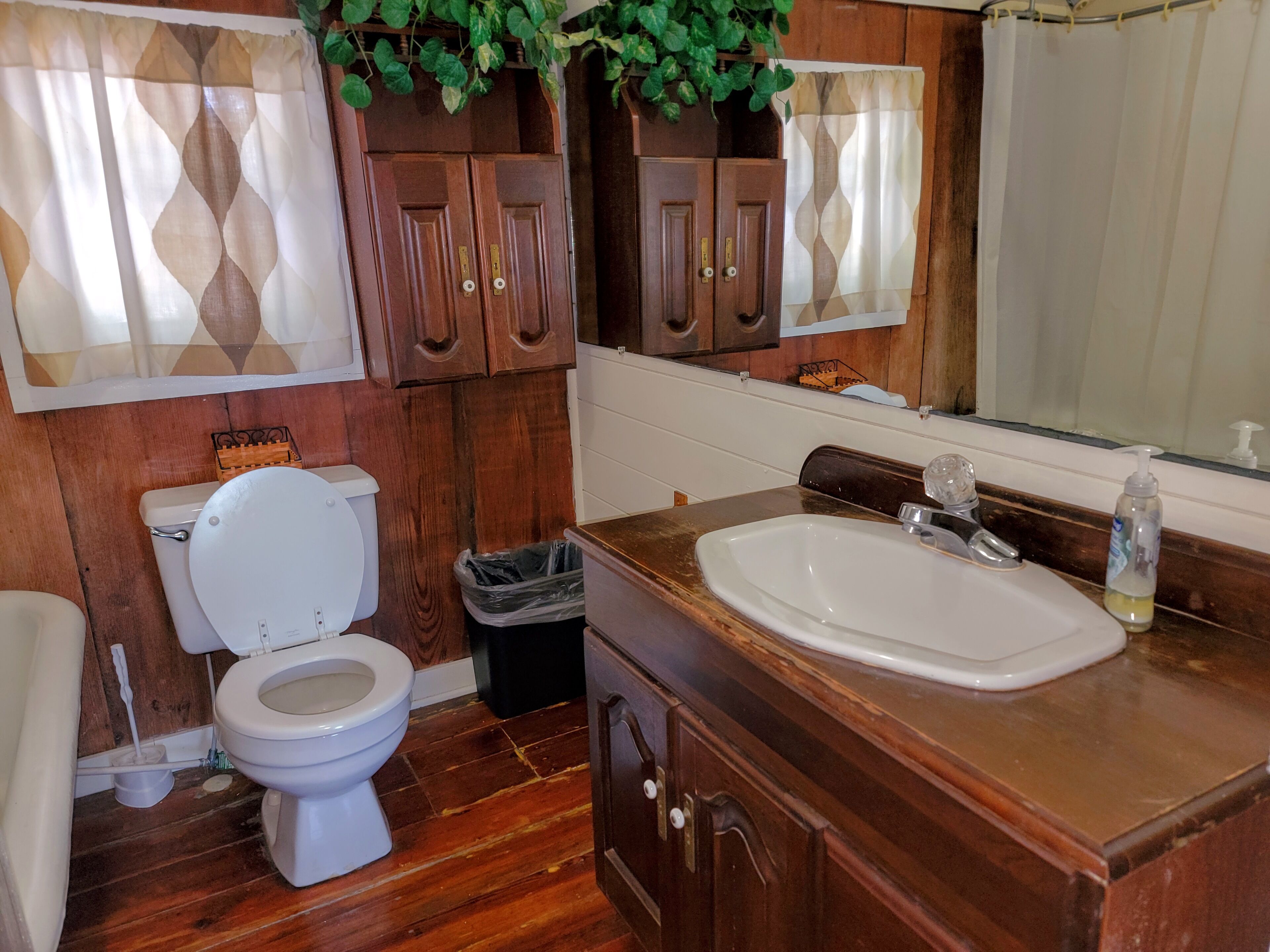 Un baño con muebles de madera, un lavamanos blanco y un inodoro.