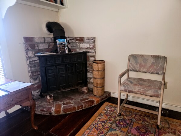 A room with a fireplace, a chair, a desk, and a patterned rug.