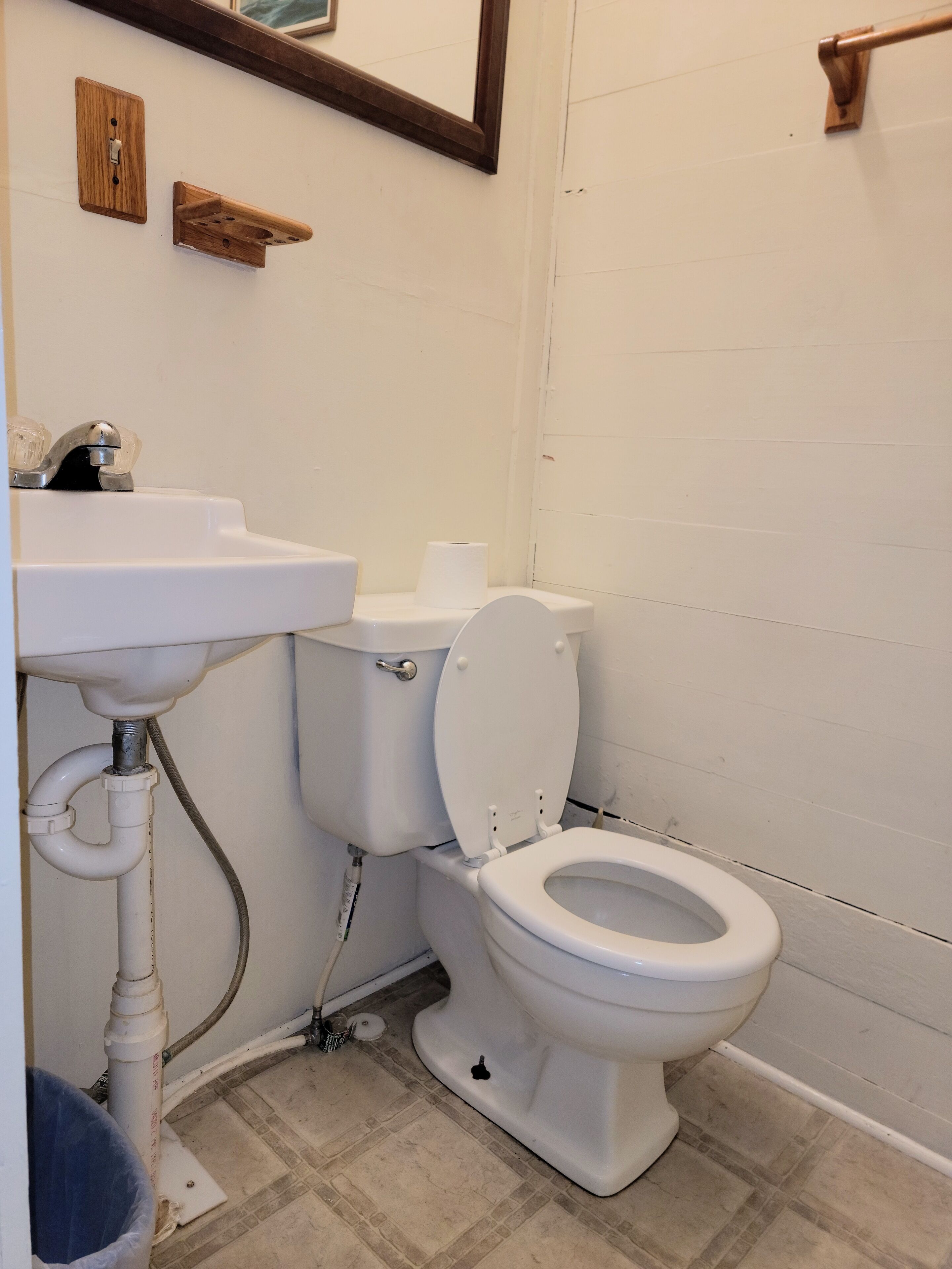 Un baño con un lavabo blanco, inodoro y espejo sobre el lavabo.