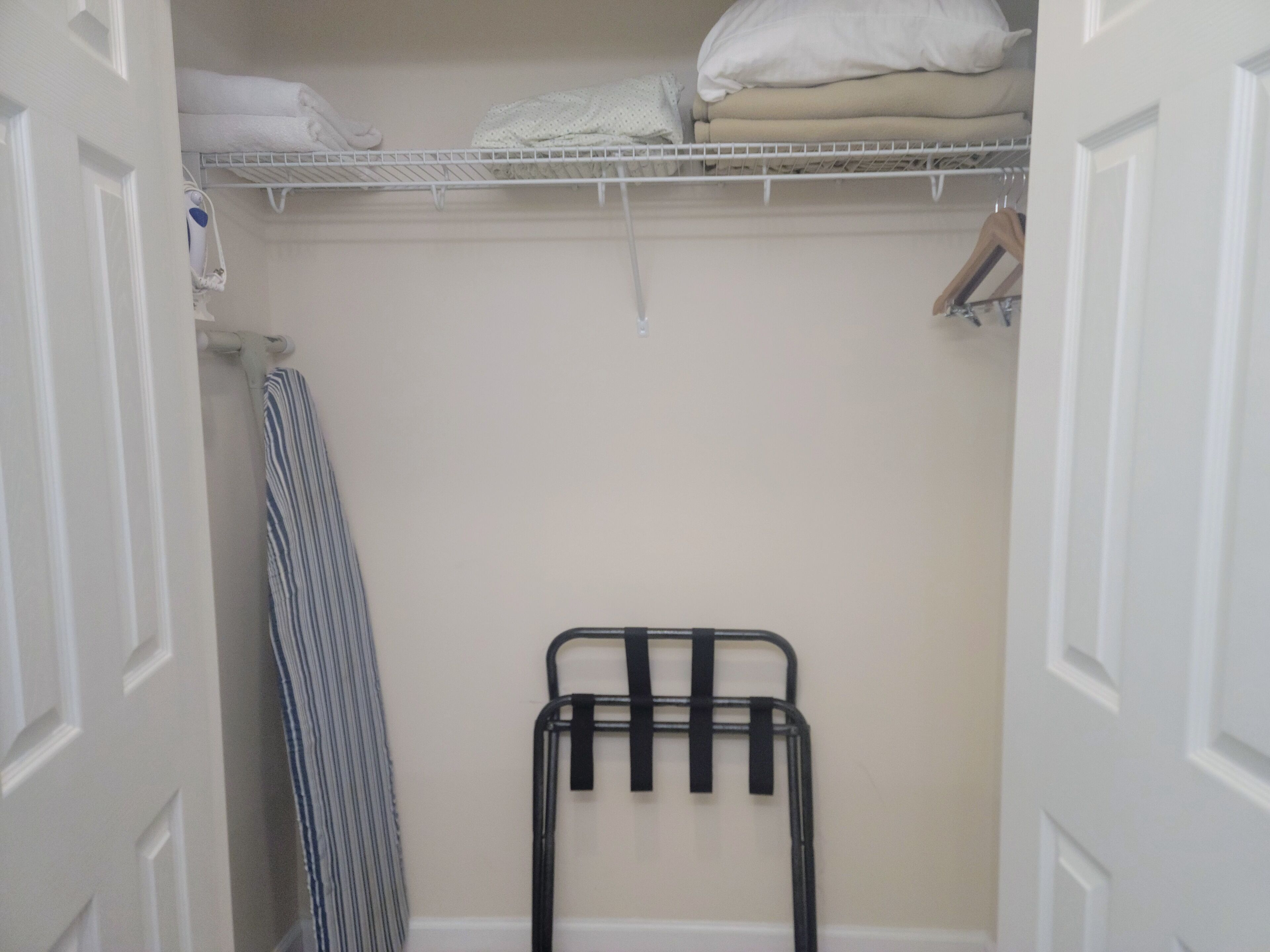 A walk-in closet with a hanging rack, shelves, and a folded towel rack.