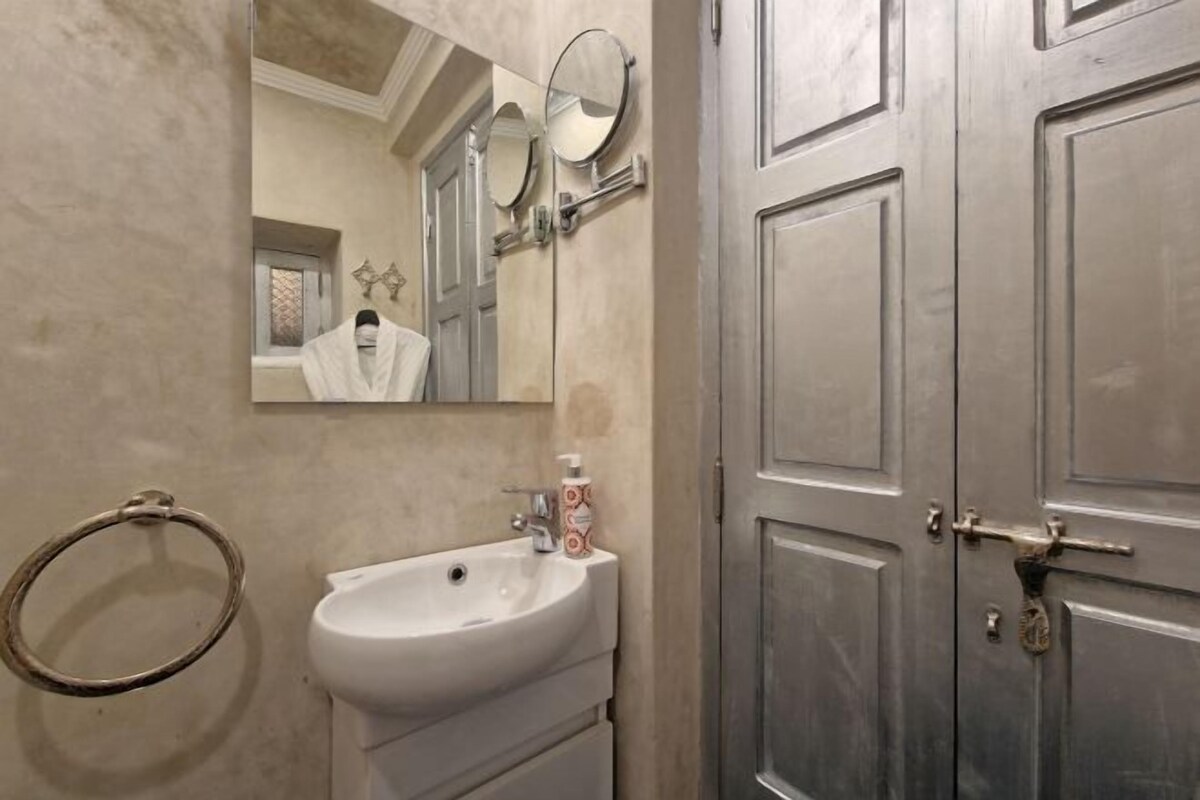 A bathroom with a sink, mirror, and a towel ring.