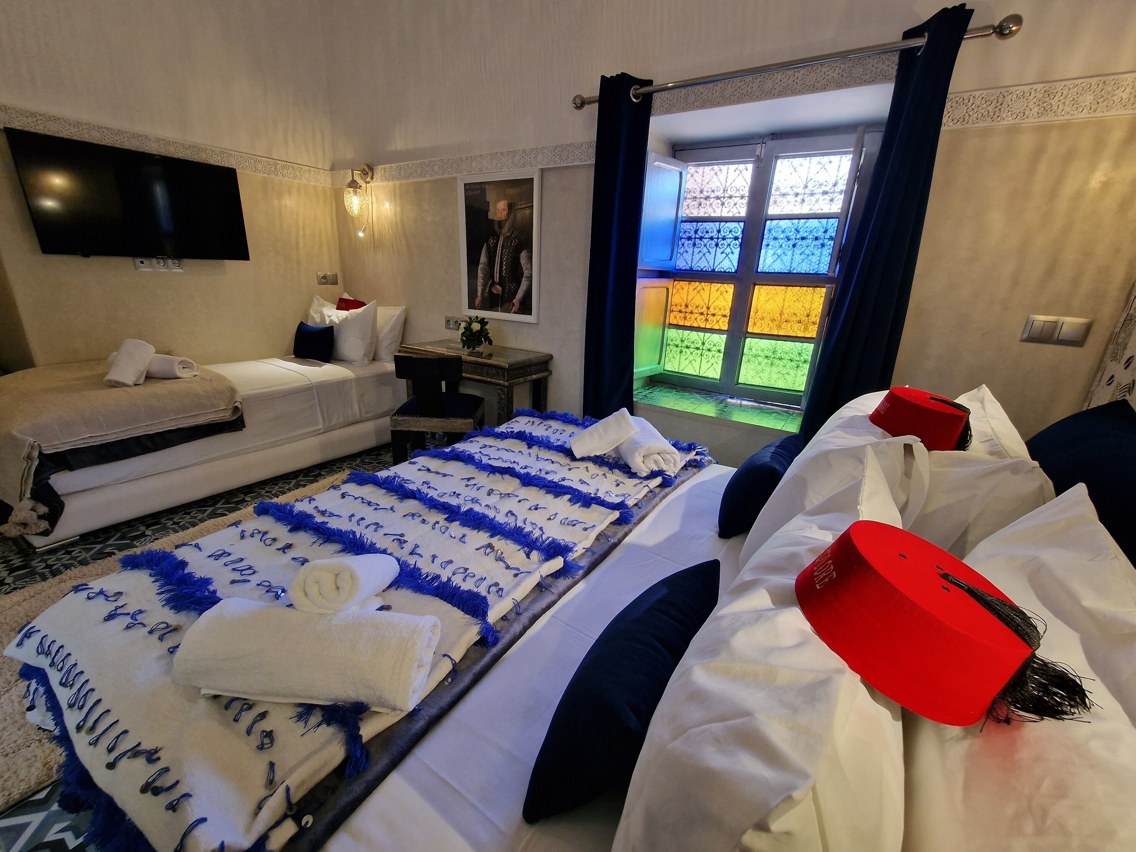A hotel room with a bed, a sofa, a TV, and a window with a view of a colorful outdoor area.