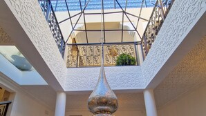 A spacious atrium with a high ceiling, ornate metal railings, and a central decorative light fixture. - Riad Explore (Marrakech)