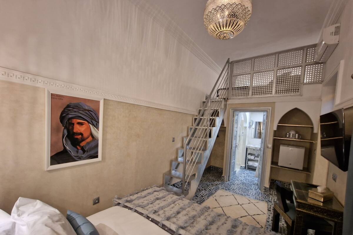 Un dormitorio con cama, escaleras, armario y lámpara en el techo.