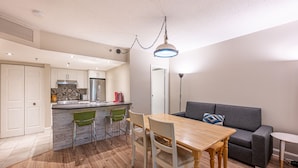 Een moderne keuken met een centraal eiland, een eettafel met stoelen en een grijze bank.