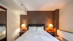 A hotel room with a large bed, two bedside tables with lamps, a mirror, and a headboard.