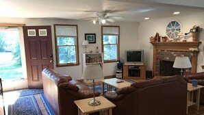 A living room with a brown leather sofa, a wooden coffee table, a TV, and a fireplace.