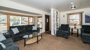 A living room with a black sofa, a glass coffee table, and a bookshelf. - Family, Group Friendly, Large Yard, Only 6 Miles To Duluth, MN!  EV Charger (Superior)