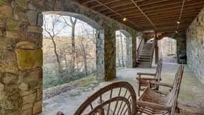 Portico con pareti in pietra, panche di legno e una scala che conduce a un livello superiore.