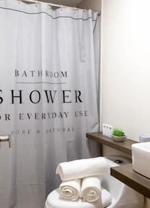 Bathroom features a shower, toilet, and a small plant, with a towel dispenser for convenience.