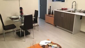 Eine kompakte Küche mit Essbereich, einer kleinen Kochinsel und einem an der Wand befestigten Fernseher.