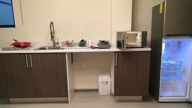 Eine Küche mit Kühlschrank, Mikrowelle, Spüle und Schränken.