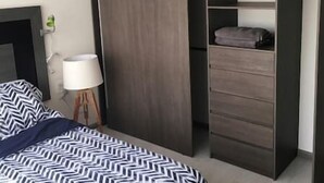 Ein Schlafzimmer mit Bett, Nachttischlampe, Kleiderschrank und Kommode.