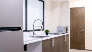 A modern kitchen with a white countertop, a stainless steel faucet, a small potted plant, and a microwave. - New and excellent conditions (Benito Juárez)
