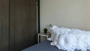 A bedroom with a bed, a small table with a plant, and a wooden wardrobe. - New and excellent conditions (Benito Juárez)