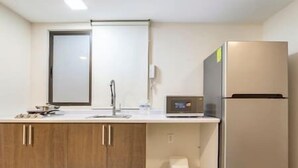 Eine kleine Küche mit Holzschränken, einem Edelstahlkühlschrank, einer Mikrowelle und einem Spülbecken.