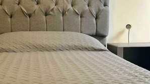 Un lit doté d’une tête de lit capitonnée et d’une couvre-lit à motifs.