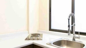 Une cuisine moderne dotée d’un évier en acier inoxydable, d’un robinet et d’une plaque de cuisson.