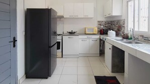Een moderne keuken met witte kasten, een zwarte koelkast, een magnetron en een spoelbak.
