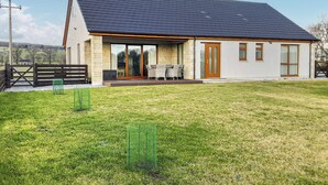 Ein modernes Haus mit Naturstein-Fassade, großen Fenstern und einer überdachten Terrasse.