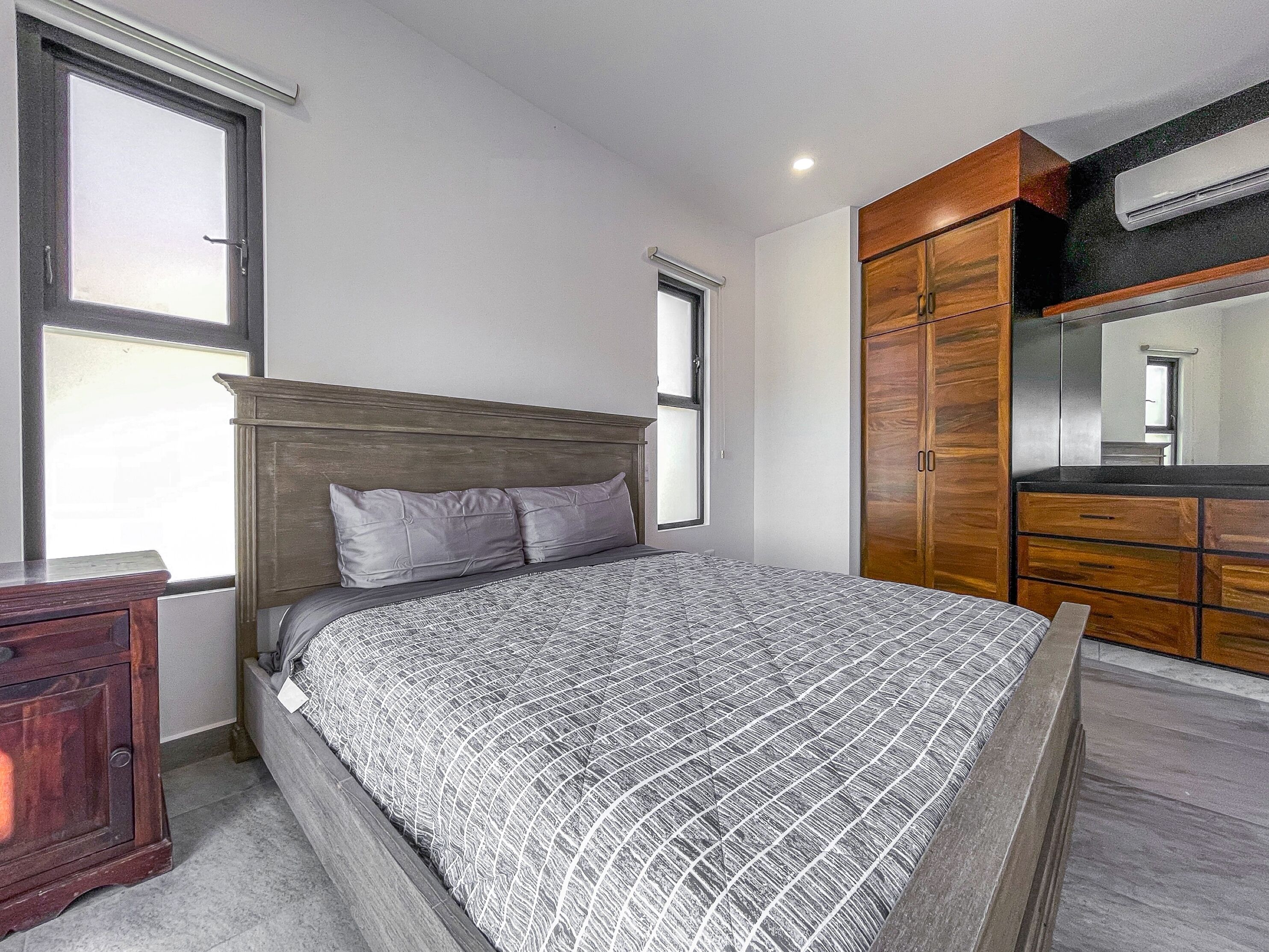Une chambre à coucher avec un lit, une armoire en bois et un grand miroir.
