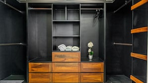Ein moderner Kleiderschrank mit Holoszillen und Regalen, eine kleine Topfpflanze und ordentlich gefaltete Handtücher.