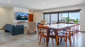 Ein geräumiges Wohnzimmer mit großem Esstisch, bequemen Sitzgelegenheiten, einem Flachbildfernseher und einem Balkon mit Aussicht.