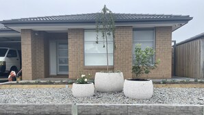 A modern house with a brick facade, large windows, and a gravel driveway.