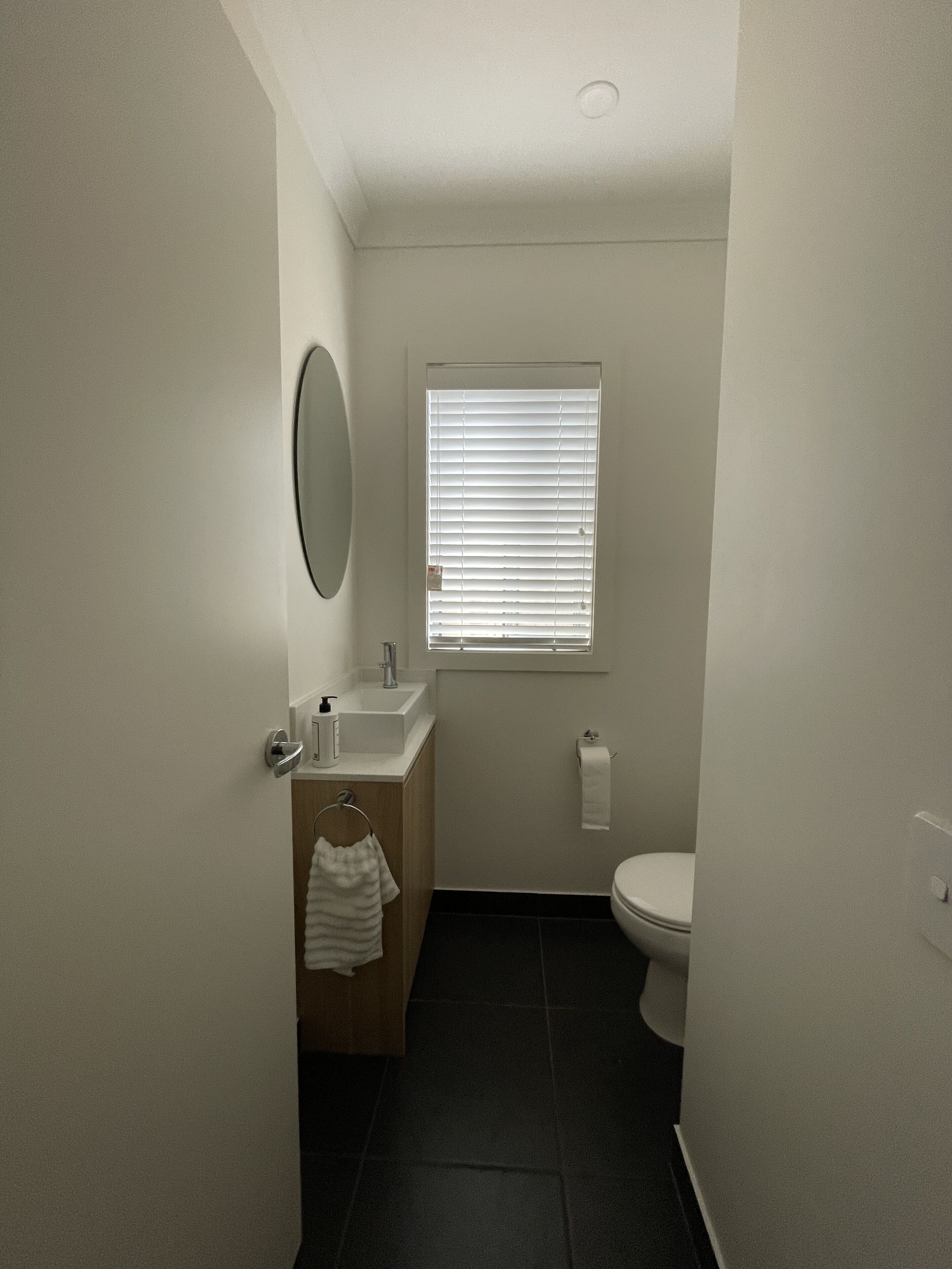A small, clean bathroom with a toilet, sink, and window.