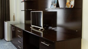 A dark wood desk with a flat-screen TV, drawers, and a shelf with books and a magazine. - VIP Room 2 - Ussat Hotel (Ashgabat)