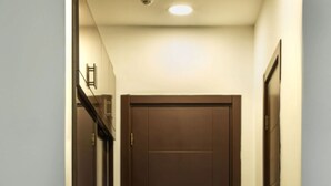 A narrow hallway with a dark brown door, a tiled floor with a diamond pattern, and a small rug at the entrance. - VIP Room 2 - Ussat Hotel (Ashgabat)