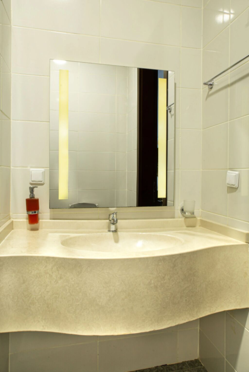 Une salle de bain avec un grand lavabo, un miroir et un porte-serviettes.