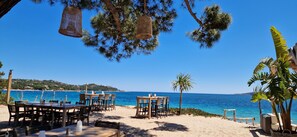 Een restaurant aan het strand met terras, met uitzicht op zee.