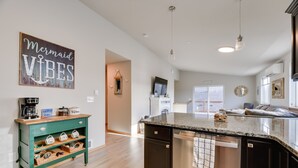 Eine moderne Küche mit einer Granit-Arbeitsplatte, einem Geschirrspüler und einem grünen Schrank mit Körben.