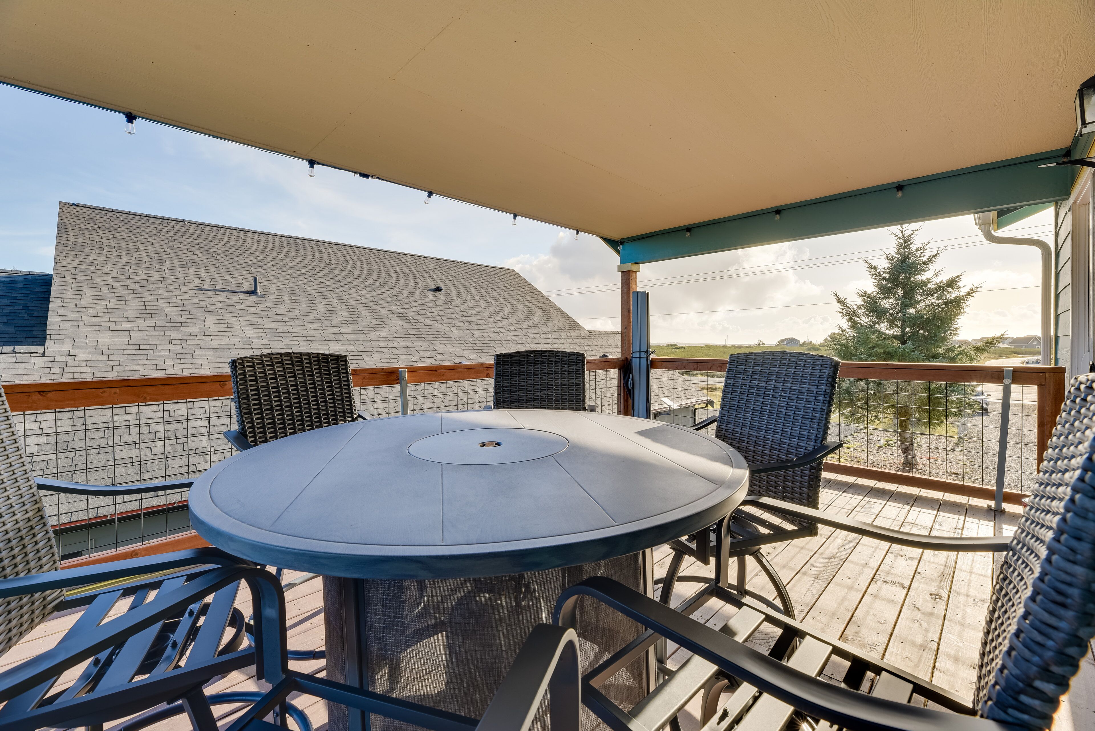 En overdækket terrasse med et rundt bord og fire stole.