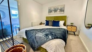 Een moderne slaapkamer met een bed, nachtkastje, stoel en uitzicht.