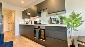 Een moderne keuken met donkere kastjes, een ingebouwde oven en een magnetron.