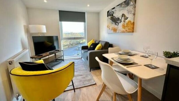 A modern living room with a dining area, a sofa, a TV, and a large window. - Coates House by Guestz (Bristol)