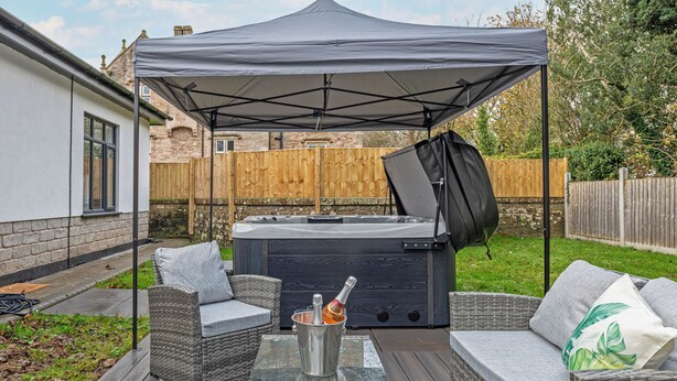 A patio area with outdoor furniture, a hot tub, and a canopy. - Eden Grove 2 Bed Holiday Retreat With Hottub (Bolton)