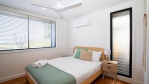 A neatly arranged bedroom with a bed, bedside table, and a ceiling fan.
