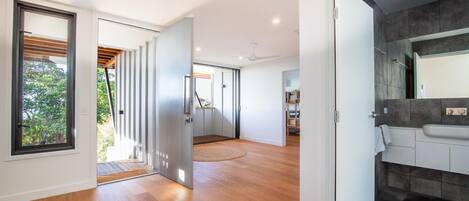 A modern interior with a wooden floor, a kitchen with a dark backsplash, and a large window.