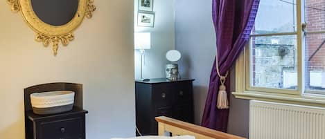 A bedroom with a bed, a dresser, a mirror, and a window with curtains.