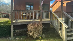 Een houten hut met een veranda, een kleine tuin en een vlag.