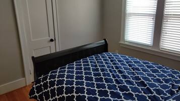 Un dormitorio con cama, puerta y ventana con persianas.