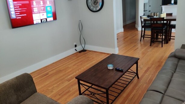 Ein Wohnzimmer mit an der Wand montiertem Fernseher, einem Couchtisch und einer Couch.