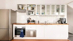 Una cocina moderna con armarios blancos, electrodomésticos de acero inoxidable y encimera de madera.