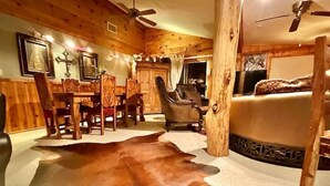 A cozy cabin interior with a dining area, a leather sofa, and a large rug. - Waterfront luxurious midcentury Log cabin (Payson)