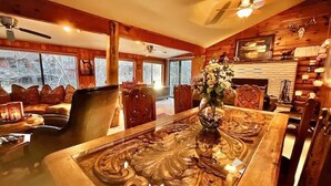 A cozy wooden interior with a dining table, chairs, and a fireplace. - Waterfront luxurious midcentury Log cabin (Payson)
