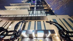A modern high-rise building with a glass facade and a prominent entrance with a curved design. - Cozy DT Fantastic Amenities View Private Parking (Calgary)